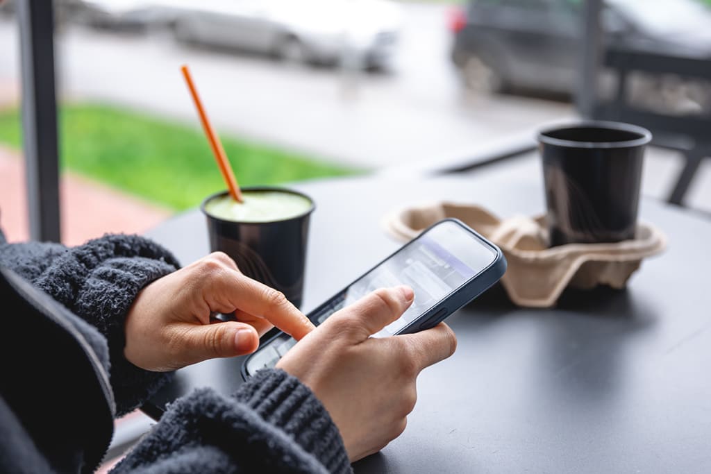 Personne utilisant smartphone avec boissons sur table