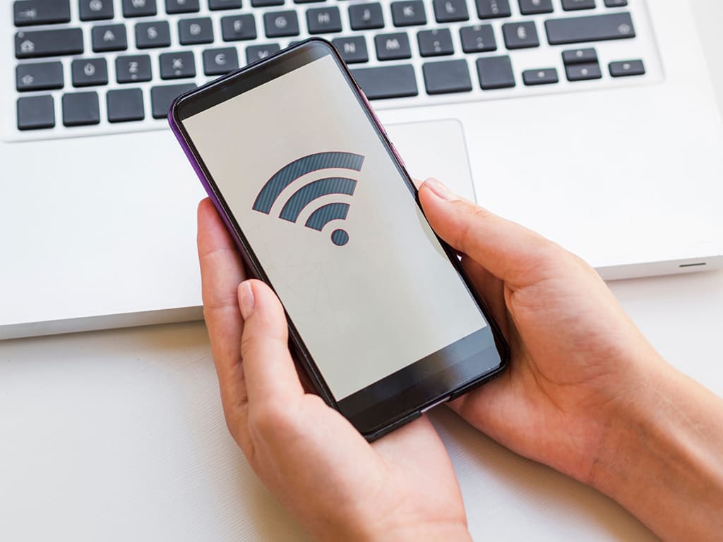 Smartphone affichant le symbole Wi-Fi près d'un ordinateur.