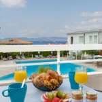 Petit-déjeuner sur terrasse avec vue sur piscine.
