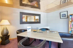 Salle de réunion moderne avec table, chaises et livres.