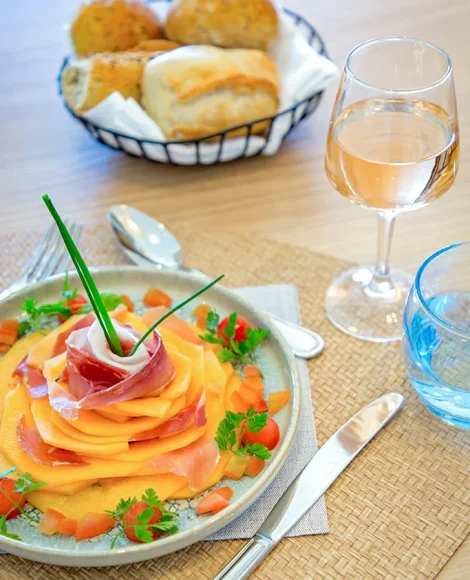 Assiette de melon et jambon avec pain et vin.