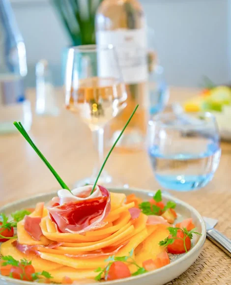 Assiette de melon et jambon cru, verre de vin.